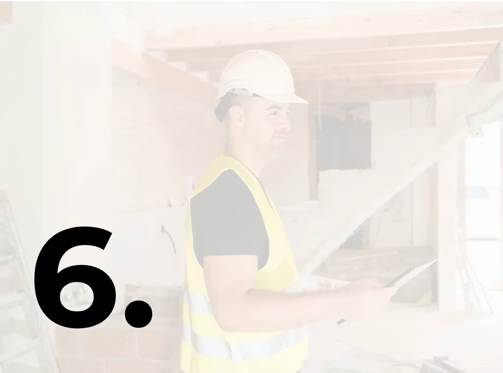 Bouwprofessional met helm en veiligheidsvest controleert werkzaamheden op de bouwplaats tijdens een verbouw- of bouwproject.